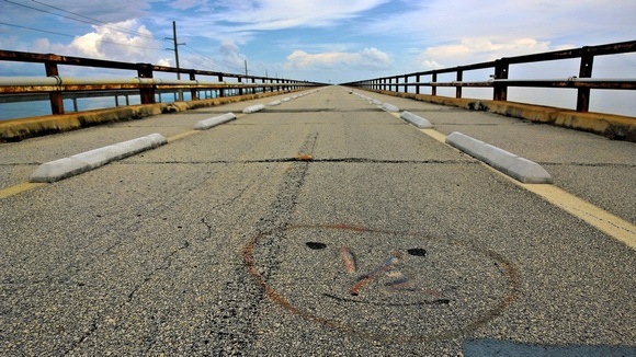 abandoned road bridge, happy face spray painted into asphalt