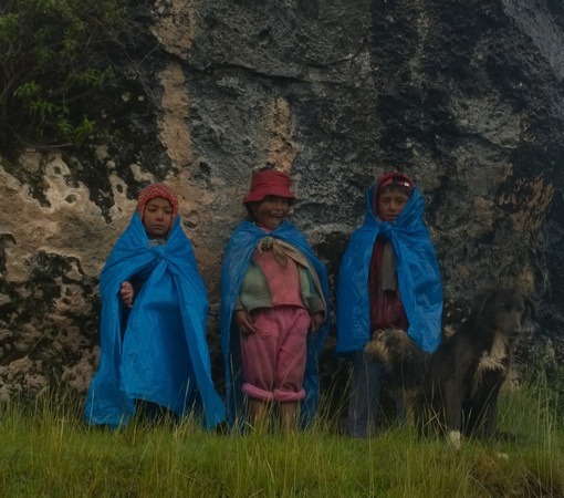 Peruvian children wearing blue tarps in the rain