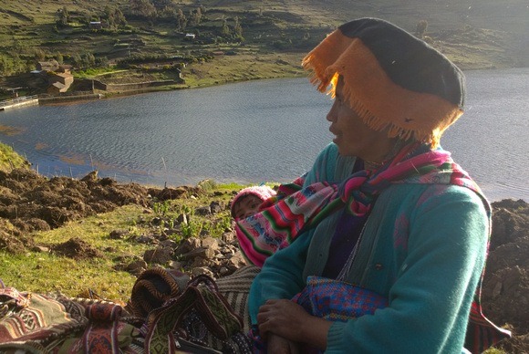 Quechua woman and baby at sunset, selling hand-woven textiles