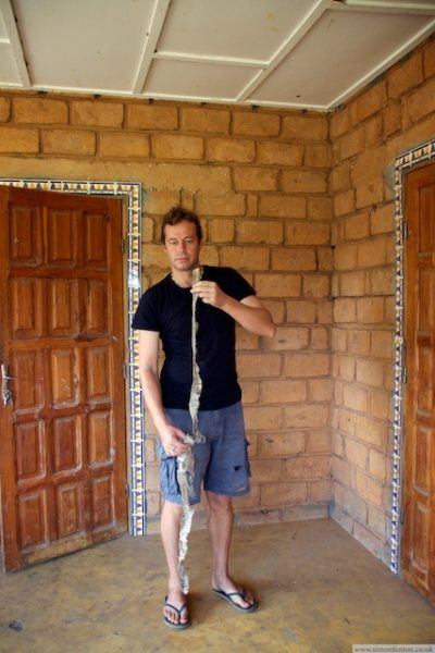 Simon Fenton in Senegal holding up a 2 metre snakeskin